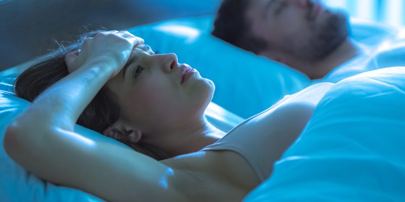 The woman with a headache lay near the man in the bed. night time